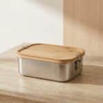 Bento japonais en acier inoxydable et bambou, posé sur une table beige
