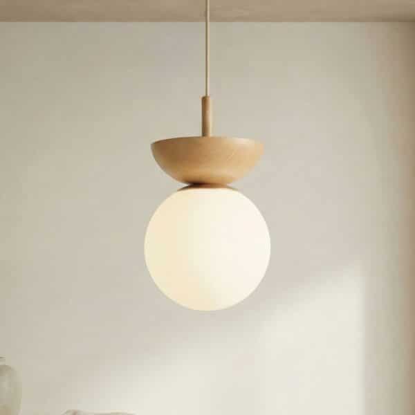 Suspension japandi boule en verre et bois lumière douce, globe blanc dépoli sous coupe en bois clair, câble noir, décor minimaliste beige.