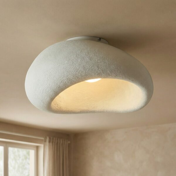 Plafonnier japandi blanc texturé, forme organique semblable à un galet, diffusant une lumière chaude indirecte, ambiance douce apaisante, style minimaliste naturel salon épuré.