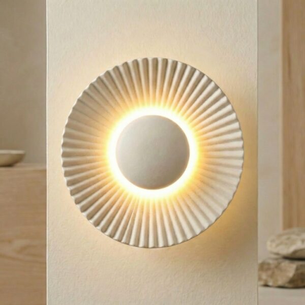 Applique murale japandi halo rayonnant blanc mat à rainures sculptées diffusant une lumière LED dorée sur mur beige.