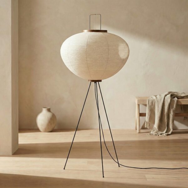 Lampadaire trépied japandi au papier blanc chaleureux dans un salon minimaliste beige avec parquet clair et vase céramique.