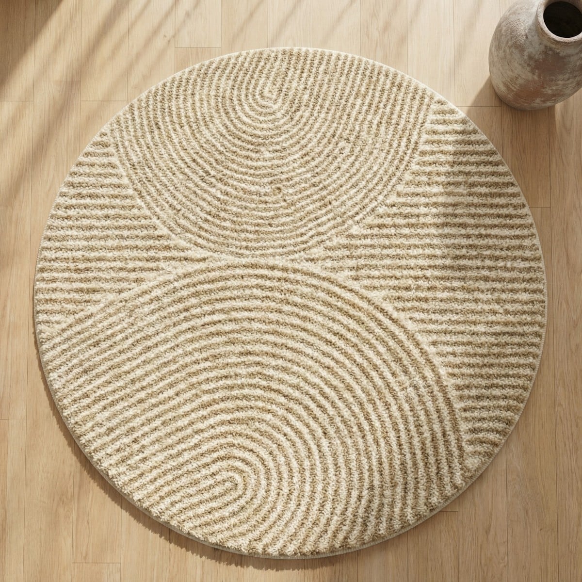 Tapis Japandi motif jardin japonais rond beige à relief circulaire texturé, posé sur parquet clair, ambiance zen douce, naturelle et minimaliste chaleureuse.