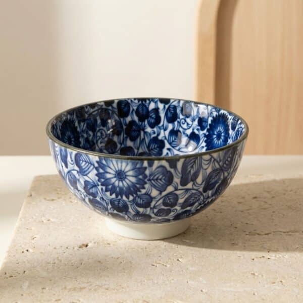 Bol japonais en céramique à motif floral blanc et bleu, sur une table beige