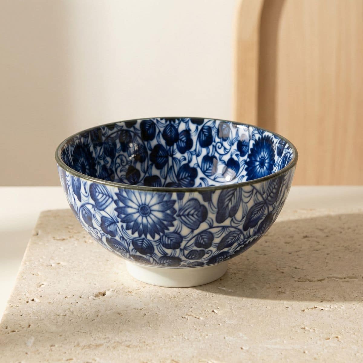 Bol japonais en céramique à motif floral blanc et bleu, sur une table beige