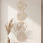 Cadre japandi inspiration jardin japonais en bois set de 4 : quatre cercles décoratifs bois clair motifs géométriques zen alignés verticalement sur mur beige, avec vase et herbe pampas ambiance minimaliste apaisante.