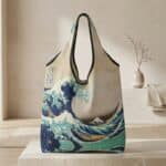 Notre sac japonais pliable à motif Hokusai beige, bleu et vert d'eau, posé sur une table en pierre.