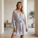 Femme portant un kimono bleu ciel et beige ceinturé à la taille, dans un salon japandi beige