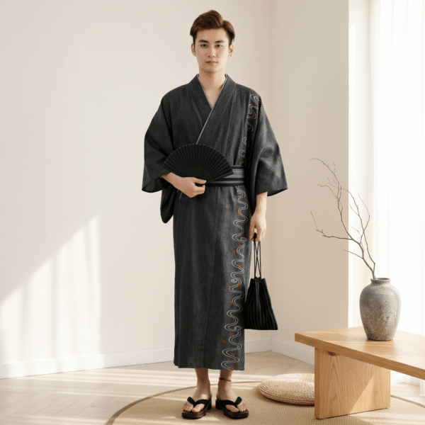 Homme portant un ensemble yukata homme brodé noir avec broderies ondulées blanches et rouges obi noir éventail et sac kinchaku.