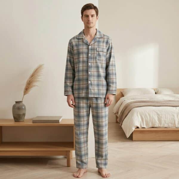 Un homme debout portant un pyjama japonais à carreaux pour homme de couleur bleu et beige, composé d'une chemise à manches longues boutonnée et d'un pantalon assorti, dans une chambre lumineuse et épurée au style minimaliste.