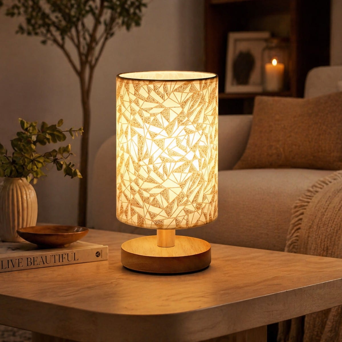 La lampe de table japandi abat-jour géométrique doré base bois cylindrique allumée sur table en bois, motifs triangles dorés rétroéclairés, salon chaleureux en fond.