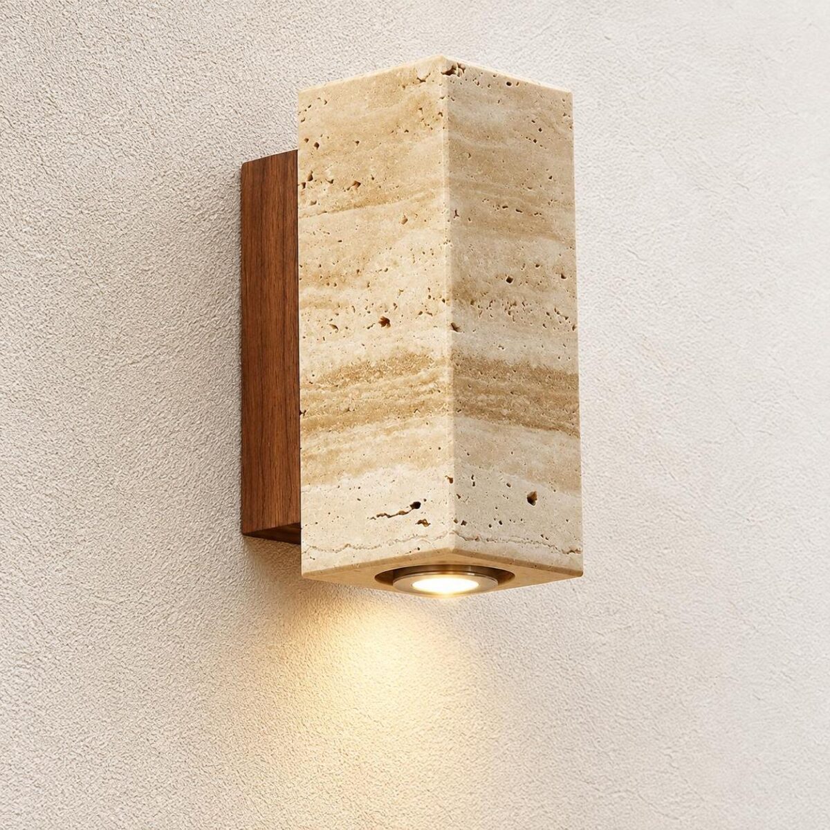 Une applique murale Japandi au format carré et lumière chaude, en pierre beige et bois, fixée sur un mur texturé et diffusant une douce lumière vers le bas.