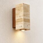 Une applique murale Japandi au format carré et lumière chaude, en pierre beige et bois, fixée sur un mur texturé et diffusant une douce lumière vers le bas.